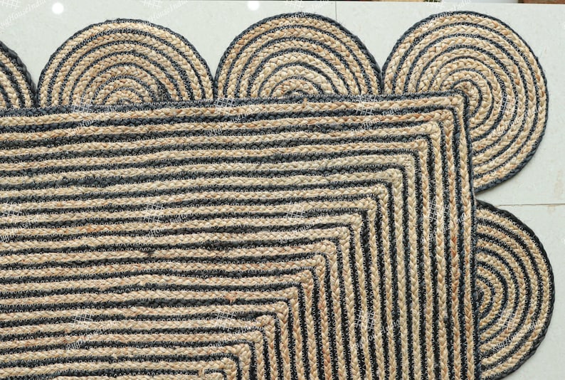 May include: A black and natural jute rug with a geometric pattern and a scalloped edge. The rug is made of natural fibers and has a rustic look.