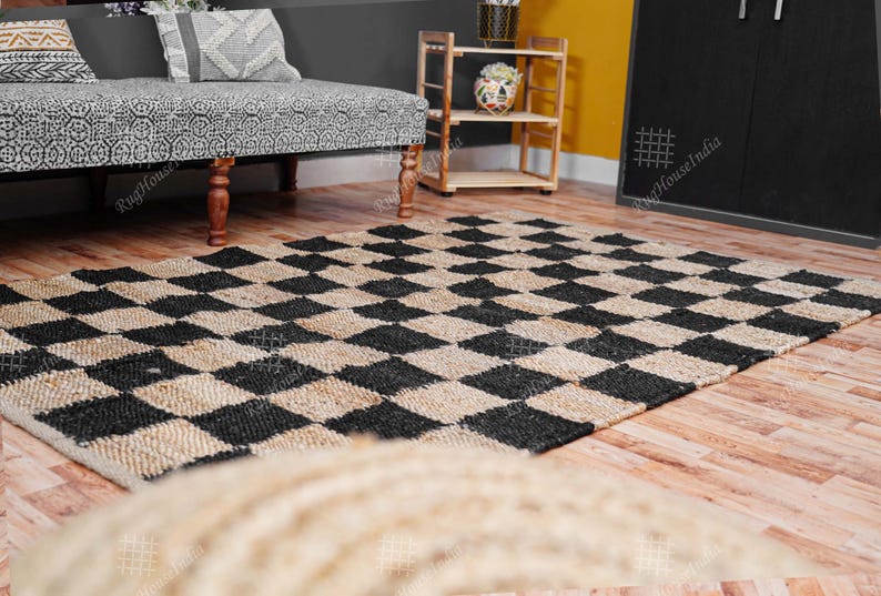 Puede incluir: Una alfombra de yute natural y negro con un patr&oacute;n de cuadros. La alfombra est&aacute; hecha de fibras naturales y tiene un aspecto r&uacute;stico.