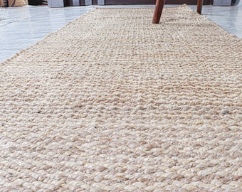 May include: A natural fiber rug made from woven jute, featuring a light brown color and a textured, slightly bumpy surface.