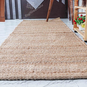 May include: A natural fiber rug made from jute, a sustainable and durable material. The rug has a light brown color and a woven texture. It is perfect for adding a touch of natural beauty to any room.