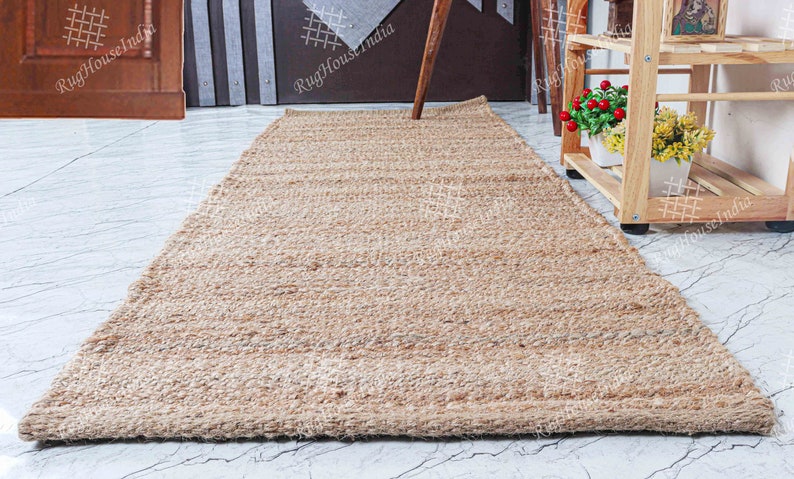 May include: A natural fiber rug made from jute, a sustainable and durable material. The rug has a light brown color and a woven texture. It is perfect for adding a touch of natural beauty to any room.