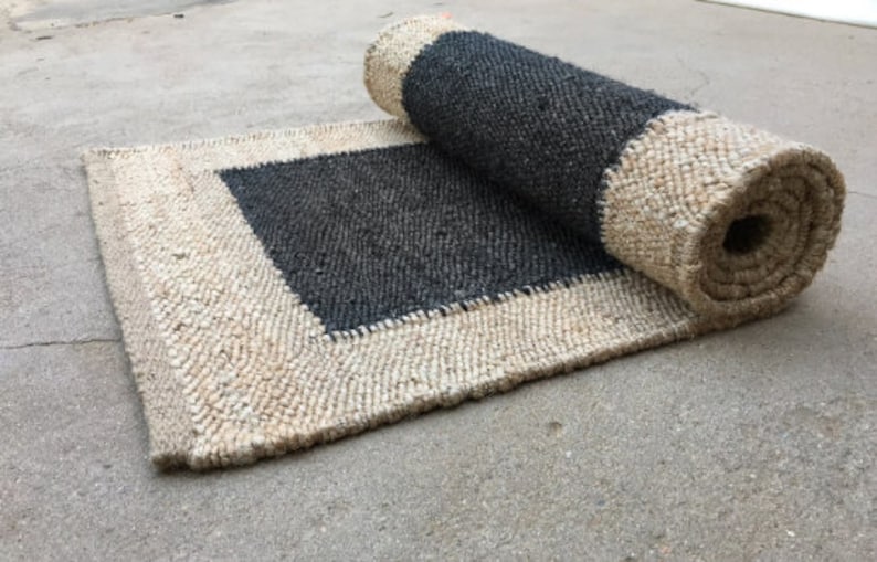 May include: A rolled-up jute rug with a black center square. The rug has a natural, woven texture.