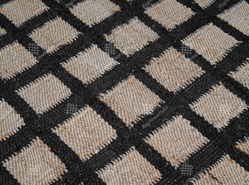 Puede incluir: Primer plano de una alfombra de yute natural y negro con un patr&oacute;n de cuadros. La alfombra est&aacute; tejida con un hilo grueso y texturizado.