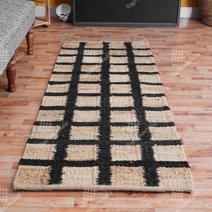 Puede incluir: Una alfombra de fibra natural con un patr&oacute;n de cuadros negros y beige. La alfombra est&aacute; hecha de yute y es perfecta para agregar un toque de textura natural a cualquier habitaci&oacute;n.