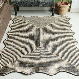 May include: A black and natural jute rug with a wavy edge and a geometric pattern. The rug is made of natural fibers and has a rustic look.