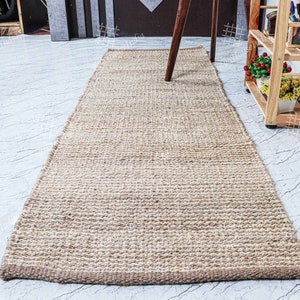 May include: A natural fiber rug made from jute, a sustainable and durable material. The rug has a light brown color and a woven texture. It is perfect for adding a touch of natural beauty to any room.