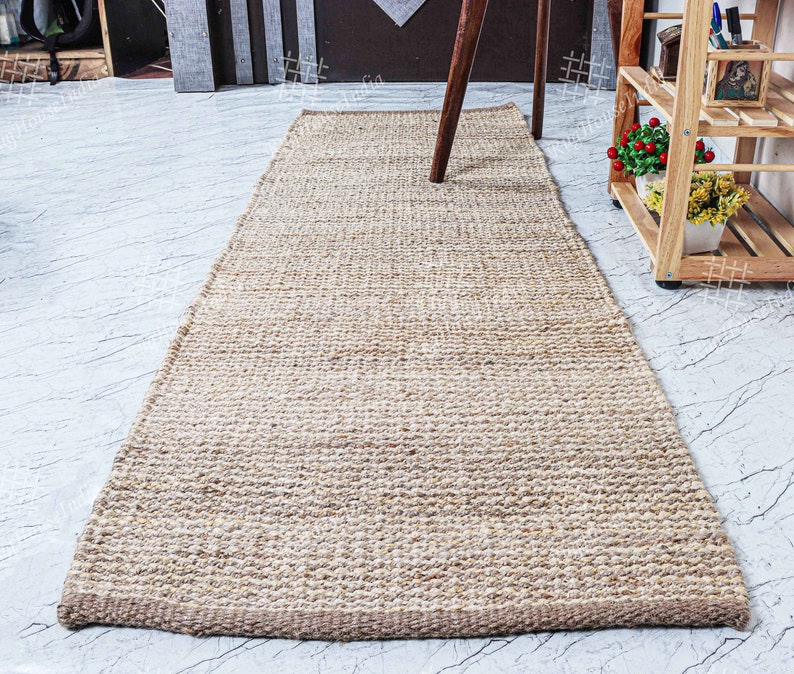 May include: A natural fiber rug made from jute, a sustainable and durable material. The rug has a light brown color and a woven texture. It is perfect for adding a touch of natural beauty to any room.