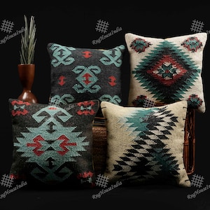 May include: Four decorative throw pillows with geometric patterns in shades of black, white, red, and teal. The pillows are made of a soft, woven fabric and have a slightly textured surface.