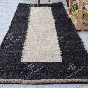May include: A black and white jute rug with a woven design. The rug has a black border and a white center. The rug is made of natural fibers and has a rustic look.