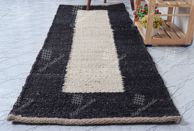 May include: A black and white jute rug with a woven design. The rug has a black border and a white center. The rug is made of natural fibers and has a rustic look.