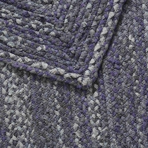 May include: Braided rug in shades of gray, white, and purple. The rug features a textured, woven design with a braided border. The color palette includes various shades of gray, with accents of white and purple.