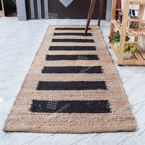 May include: A natural fiber rug with black and tan stripes. The rug is made of jute and has a woven texture.