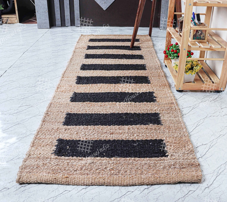 May include: A natural fiber rug with black and tan stripes. The rug is made of jute and has a woven texture.