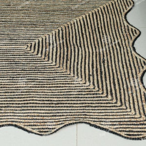 May include: A black and natural jute rug with a wavy edge and a geometric pattern. The rug is made of natural fibers and has a rustic look.