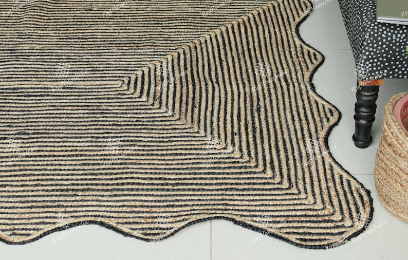 May include: A black and natural jute rug with a wavy edge and a geometric pattern. The rug is made of natural fibers and has a rustic look.