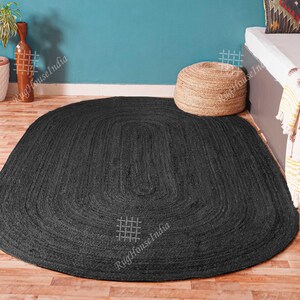 May include: An oval-shaped area rug in a solid black color, featuring a braided texture throughout its surface. The rug is constructed with concentric loops that follow the oval outline, creating a uniform and consistent pattern across the entire piece.