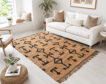 Puede incluir: Una alfombra rectangular con una base de yute de color tostado natural y un patrón geométrico repetitivo en negro. La alfombra tiene una superficie tejida texturizada y está rematada con flecos cortos y deshilachados en los bordes cortos.