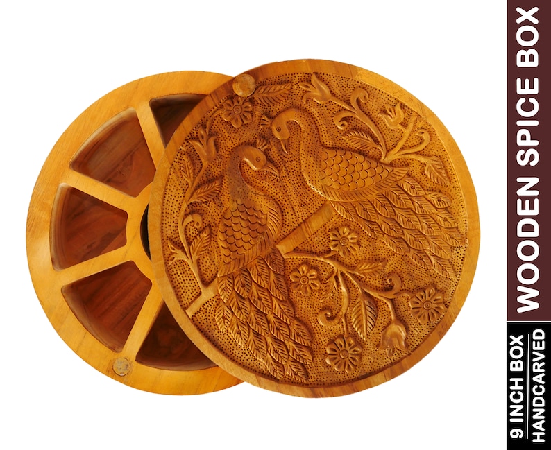 May include: A round wooden spice box with a hand-carved lid featuring two peacocks on a branch with flowers. The box has six compartments for storing spices.