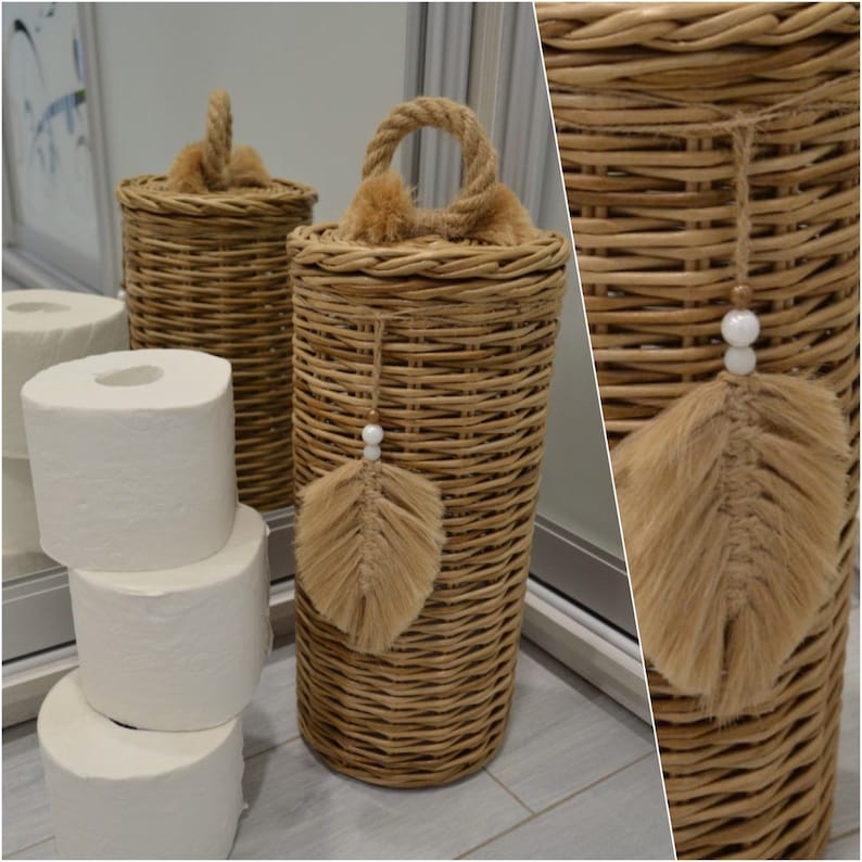 Puede incluir: Dos cestas de mimbre tejidas con asas de cuerda y un borla de plumas marr&oacute;n. Las cestas se utilizan para guardar rollos de papel higi&eacute;nico.
