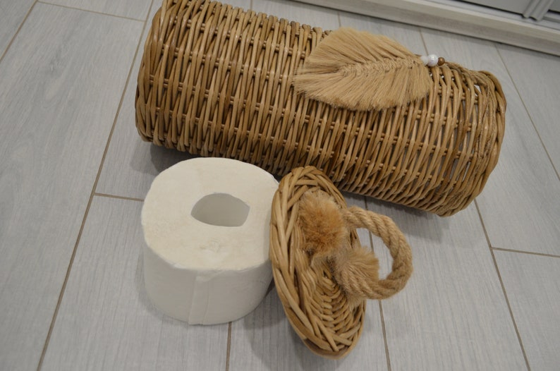 Puede incluir: Una cesta de mimbre con tapa y borla. La cesta est&aacute; vac&iacute;a y la tapa est&aacute; abierta. La cesta est&aacute; sobre un suelo de madera clara.