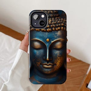 Puede incluir: Una funda para teléfono azul y dorada con una imagen detallada de una estatua de Buda. La funda tiene un recorte para el objetivo de la cámara.