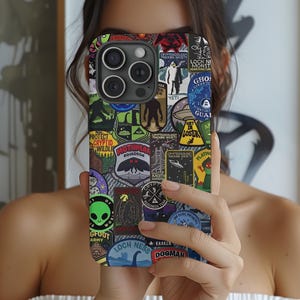 May include: A smartphone case with a collage of cryptid-themed patches. The patches feature images of the Mothman, Loch Ness Monster, Bigfoot, and other mysterious creatures. The case has a black background and a glossy finish.