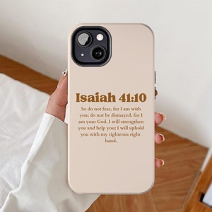 Puede incluir: Funda de teléfono beige con el texto "Isaías 41:10" en marrón. El texto es un versículo bíblico, con el versículo completo impreso debajo del título. La funda del teléfono tiene una lente de cámara negra.