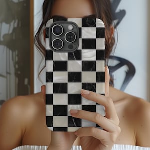 May include: A smartphone case featuring a black and white chequered design. The case has a glossy finish and a marble-effect texture. The phone case has a camera module with three lenses.