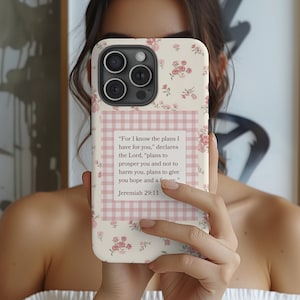 May include: A floral iPhone case with a cream background and pink roses. The case features a pink and white gingham square with the text "For I know the plans I have for you," from Jeremiah 29:11.