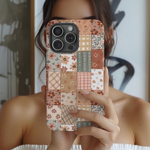 Puede incluir: Una funda de teléfono con un diseño de patchwork que presenta varios patrones florales y geométricos en tonos marrones, rosas y verdes.