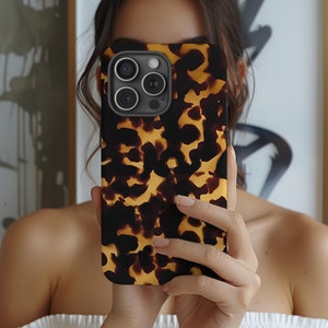 May include: A brown and black tortoiseshell phone case with a camera lens cutout. The case has a textured, patterned design.
