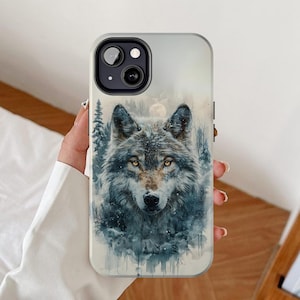 May include: A white phone case with a watercolor illustration of a wolf in a snowy forest. The wolf has a gray and white coat and is looking directly at the viewer. The phone case has a black camera cutout.