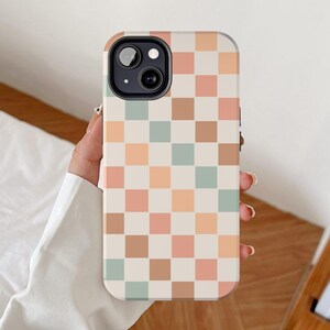 May include: A white phone case with a checkered pattern in shades of brown, peach, and light blue.