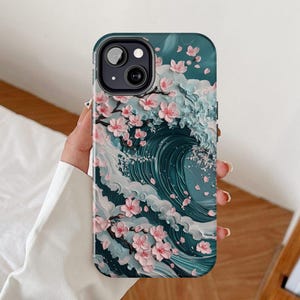 May include: A teal phone case featuring a 3D design of a Japanese wave with cherry blossoms. The case has a dark teal background with a white and teal wave design. Pink cherry blossoms are scattered across the case.