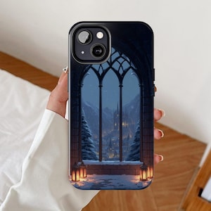 May include: A black smartphone case featuring a printed design of a gothic arched window looking out onto a snowy winter landscape at night. The scene includes a distant castle, pine trees, and two glowing lanterns on a stone ledge.