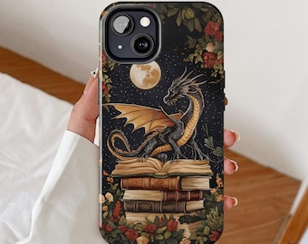 May include: A black and gold dragon with wings sits on top of a stack of old books. The dragon is surrounded by flowers and leaves. The background is a dark blue with stars and a moon.