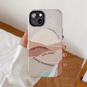 Peut inclure: Une coque de téléphone avec un fond beige et un design abstrait coloré. Le texte "his mercies are new every morning" et "Lamentations 3:23" sont imprimés sur la coque.