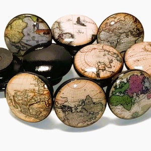 May include: A collection of round cabinet knobs featuring vintage map illustrations on their faces. Each knob has a smooth, glossy surface with detailed cartographic prints in muted tones of beige, green, and brown, set against black bases.