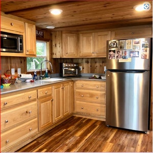以下が含まれることがあります： 木製のキャビネットとステンレス製の冷蔵庫があるキッチン。キャビネットにはブラッシュニッケルの金具が付いています。カウンタートップはライトグレーのラミネートです。床はライトブラウンの木製ラミネートです。カウンターには小さなトースターオーブンがあります。