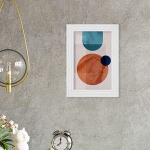 May include: Abstract art print with a white frame. The print features a blue and orange geometric design with a white background.