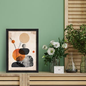May include: A framed abstract print with a beige background and black, orange, and brown geometric shapes. The print is in a black frame and is hanging on a green wall.