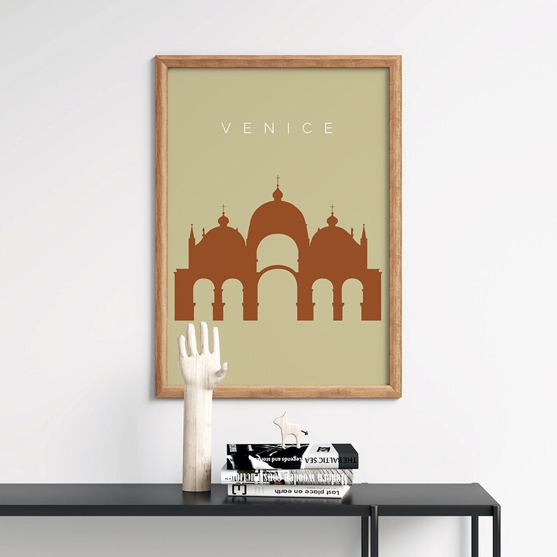 May include: A framed print with a beige background and a brown silhouette of a building with multiple domes. The text "VENICE" is printed in brown at the top of the print.