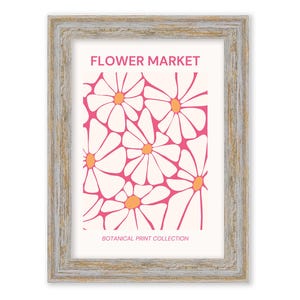 May include: A framed print with a pink and white floral design. The print features a repeating pattern of stylized white daisies with orange centers on a pink background. The text "FLOWER MARKET" and "BOTANICAL PRINT COLLECTION" is printed below the floral design.