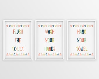 May include: Three white framed prints with colorful geometric borders and text. The first print says "Flush the Toilet", the second print says "Wash your Hands", and the third print says "Hang your Towel".
