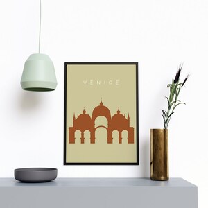 May include: A framed print with a beige background and a brown silhouette of a building with the word "VENICE" in white text at the top.