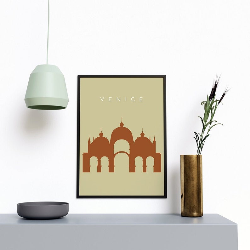 May include: A framed print with a beige background and a brown silhouette of a building with the word "VENICE" in white text at the top.