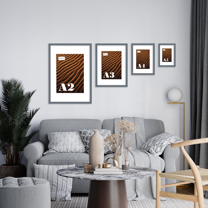 May include: Four gray picture frames with white mats on a white wall. The frames are arranged in a descending size order from left to right. The largest frame is labeled "A2", the next largest is labeled "A3", the next is labeled "A4", and the smallest is labeled "A5".