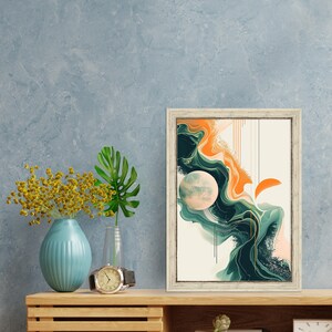 May include: A framed abstract art print with a white background and a swirling design in shades of green, orange, and pink. The print is in a white frame and is hanging on a blue wall.