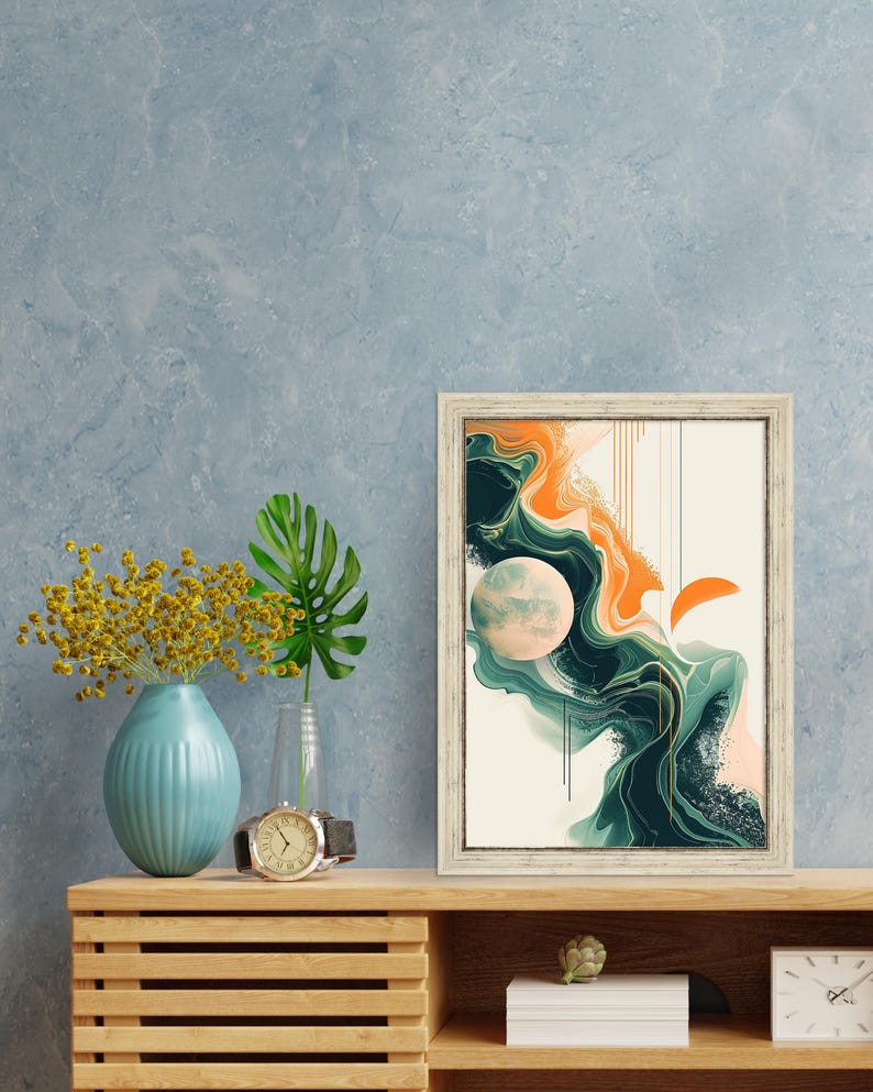 May include: A framed abstract art print with a white background and a swirling design in shades of green, orange, and pink. The print is in a white frame and is hanging on a blue wall.