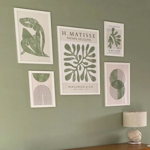 Op de afbeelding: Een wandgalerij met vijf ingelijste prints met abstracte ontwerpen in tinten groen en wit. De prints bevatten de tekst "H. Matisse Papiers Decoupes" en "Berggruen & Cie" samen met een gestileerd bladerontwerp en een geometrisch ontwerp.